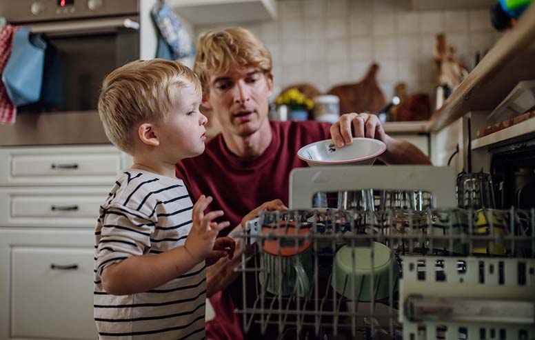 Pikkupoika ja isä tyhjentävät astianpesukonetta